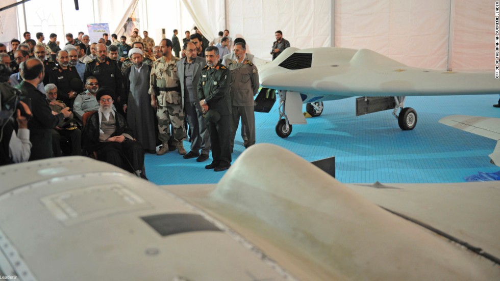 Iranian Supreme Leader Ayatollah Ali Khamenei, seated left, listens to an official during his visit to an aerospace exhibition in Tehran, Iran, on Sunday, May 11. The exhibition revealed an advanced CIA spy drone, at front, captured in 2011 by Iran, and its Iranian-made copy, at back.