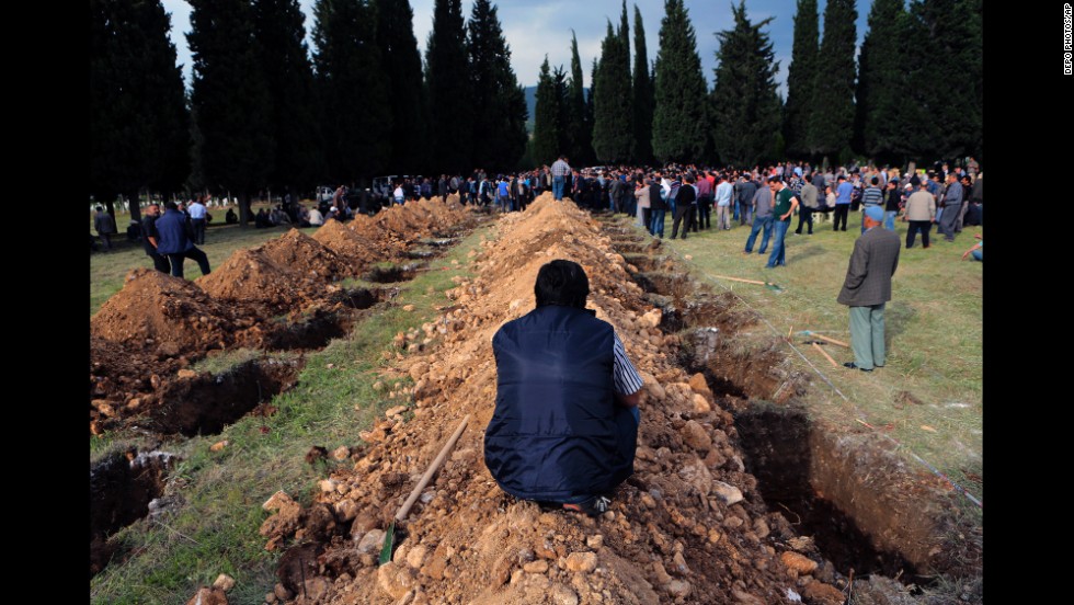 People gather near rows of open graves for victims in Soma on May 14.