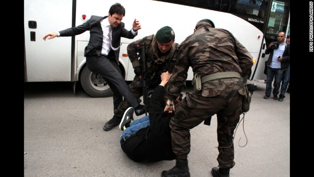 An aide to Turkish Prime Minister Recep Tayyip Erdogan kicks a person who is being wrestled to the ground by two police officers during protests in Manisa, Turkey, on Wednesday, May 14.