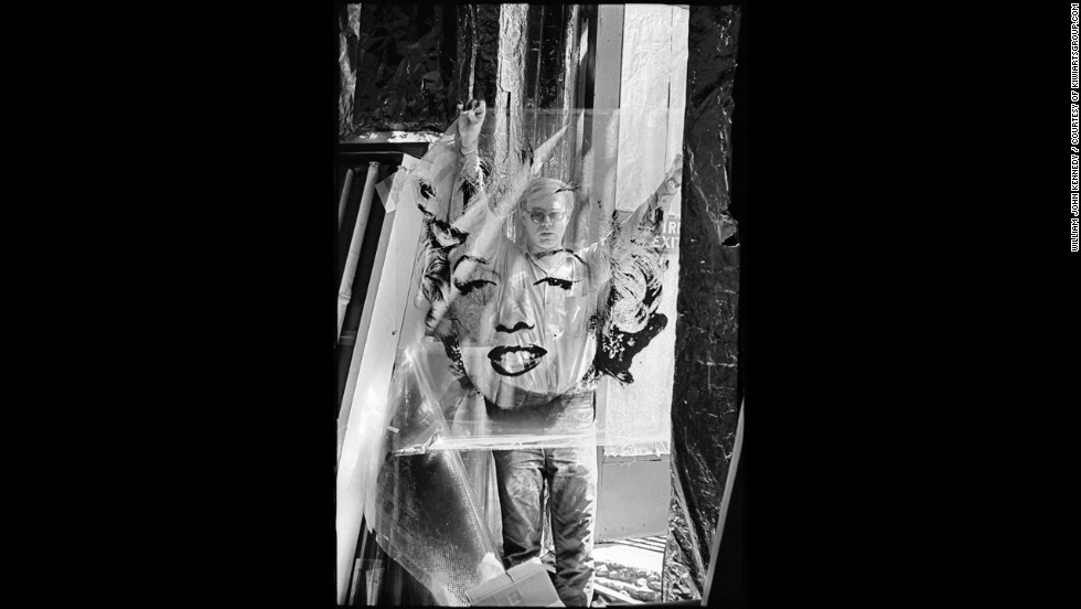 Artist Andy Warhol stands in the doorway of his studio, the Factory, in 1964, holding the acetate he used to make his famous Marilyn Monroe paintings. Warhol&#39;s work centered on famous personalities and iconic American objects, making him a leading figure in the pop art movement. 