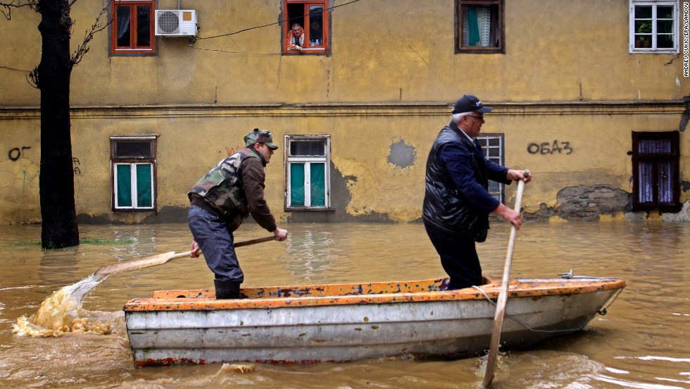Men paddle through the flooded streets of Obrenovac on Friday, May 16. Authorities estimate that 90% of the town has been flooded.