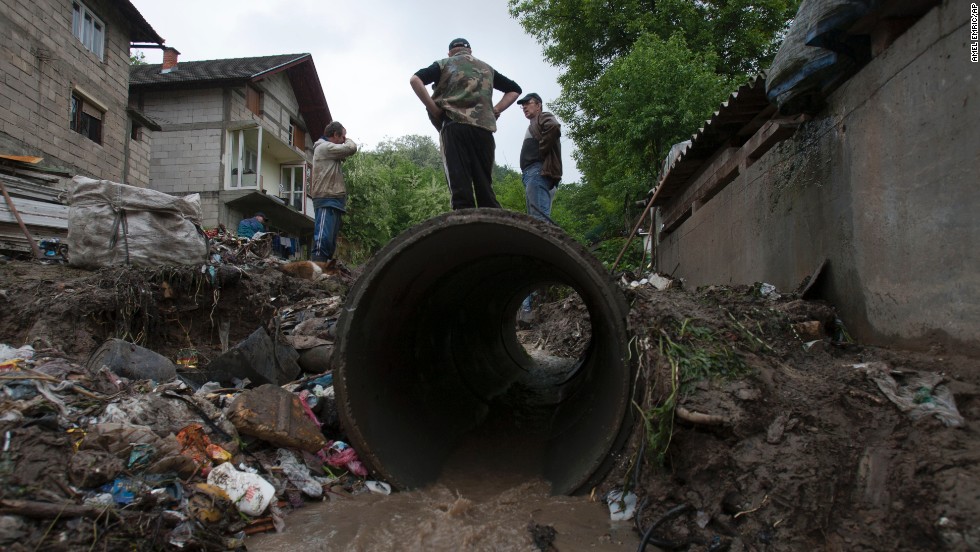 People work to clear debris from a small stream that was clogged and causing localized flooding near their homes in Tuzla, Bosnia-Herzegovina, on Sunday, May 12.