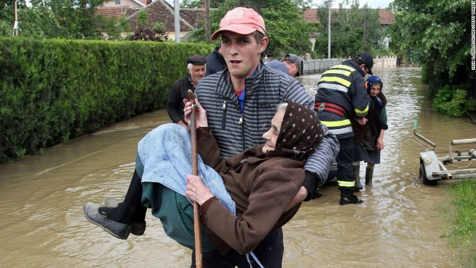 A rescuer carries an elderly woman out of her flooded house in Obrez, Serbia, on Saturday, May 17.