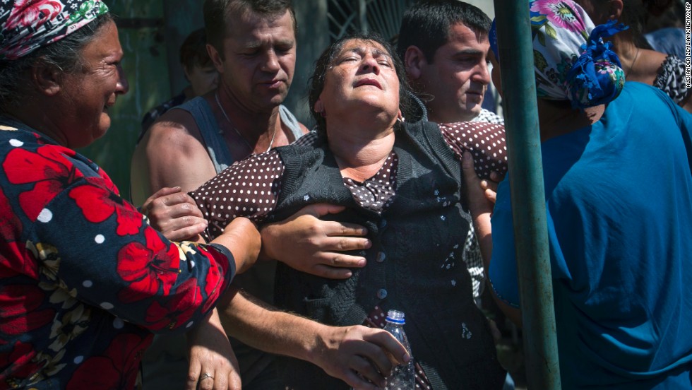 Local citizens help support a woman at a rally protesting shelling by Ukrainian government forces in the village of Semyonovka, Ukraine, on Thursday, May 22.