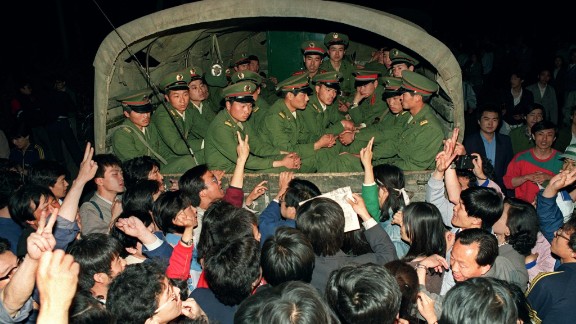 May 20, 1989, pro-democracy demonstrators raise their fists and flash the victory sign while stopping a military truck filled with soldiers on its way to Tiananmen Square.