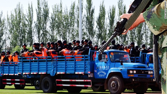 Terror suspects, in orange jumpsuits, held by security forces.