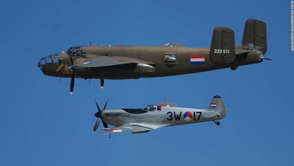 A Dutch B-25 Mitchell, top, and Spitfire fly over Arromanches-les-Bains, France, during a joint French-Dutch ceremony.