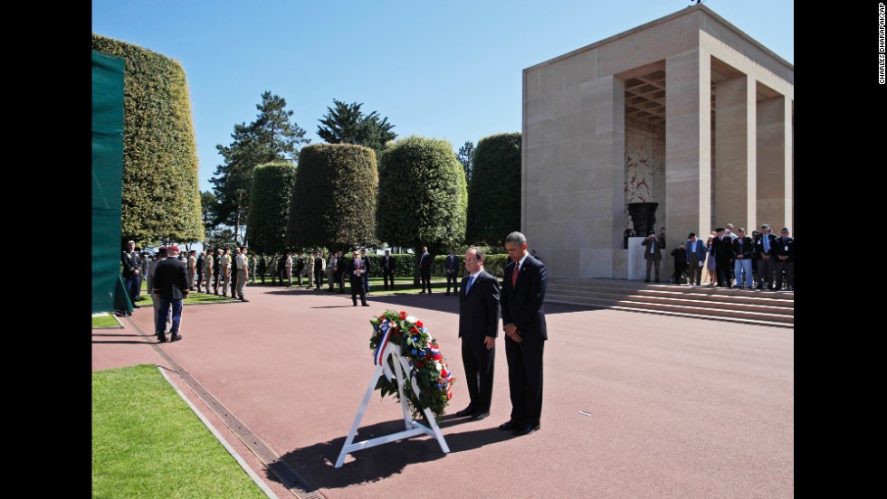 President Barack Obama and French President Francois Hollande pause for a moment of silence after laying a wreath at the Normandy American Cemetery in Colleville-sur-Mer, France, on Friday, June 6, the 70th anniversary of D-Day. Obama&#39;s travel agenda also includes Poland and Belgium.