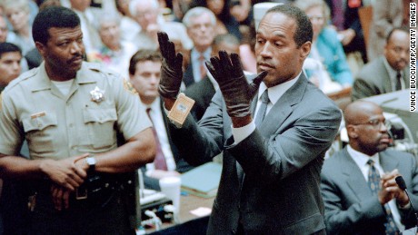 O.J. Simpson looks at a new pair of Aris extra-large gloves which the prosecutors had him put on for the jury 21 June 1995 during his double murder trial in Los Angeles. The gloves were the same type found at the Bundy murder scene and the O.J. Simpson estate.     AFP PHOTO VINCE BUCCI        (Photo credit should read VINCE BUCCI/AFP/Getty Images)