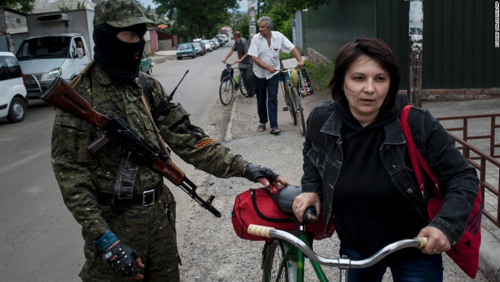 A pro-Russian fighter in Slovyansk checks a woman&#39;s documents as she leaves the city on Thursday, June 12.