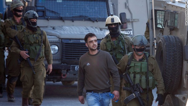 Israeli soldiers looking for three teenagers arrest a Palestinian man in the West Bank city of Hebron on Saturday, June 14.
