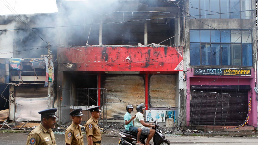 Police officers on a street in Aluthgama as shops burn. A curfew was put in place to prevent further violence.