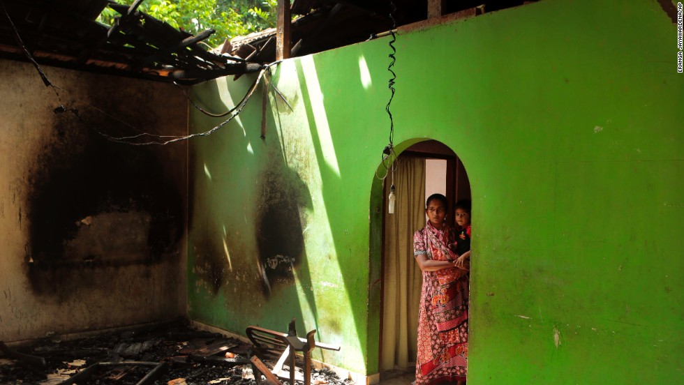 A Muslim mother and child take in damage to their house.