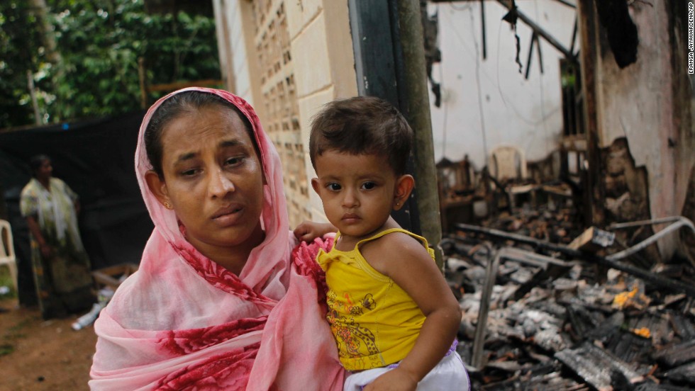 A Sri Lankan Muslim woman carries her daughter outside her burnt house after at least  three Muslims were killed and 80 injured in clashes with Buddhists last month. The sectarian riots in and around the town of Aluthgama, in southern Sri Lanka, followed demonstrations by the hardline Buddhist group Bodu Bala Sena, police said. Homes and shops were looted and burned.