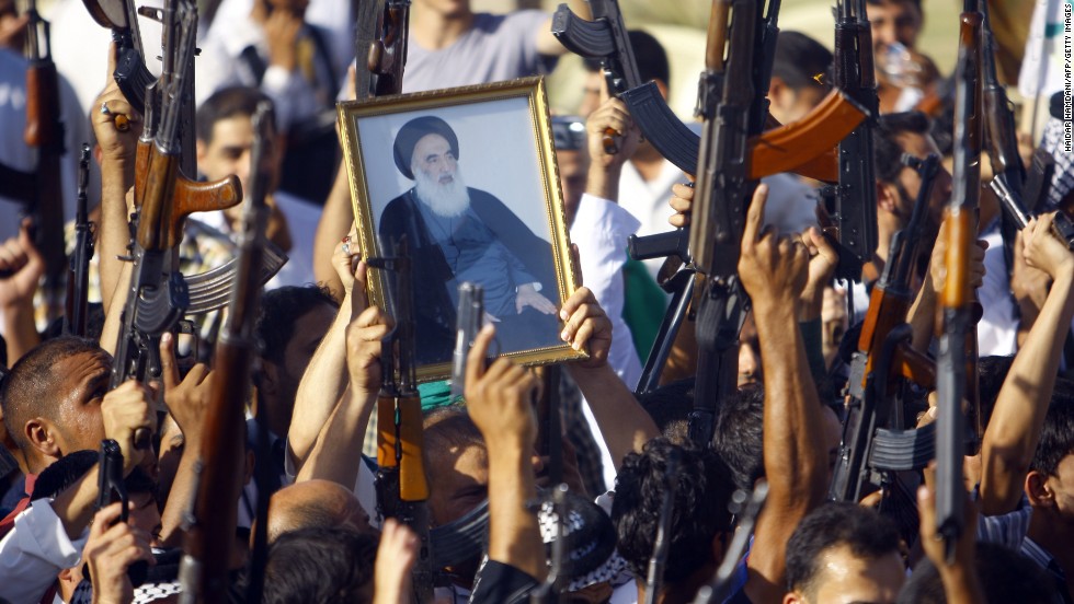 Iraqi Shiite tribesmen brandish their weapons and a poster of Shiite cleric Grand Ayatollah Ali al-Sistani in June 2014, as they gather to show their willingness to join Iraqi security forces in the fight against militants who&#39;d taken over several northern Iraqi cities.