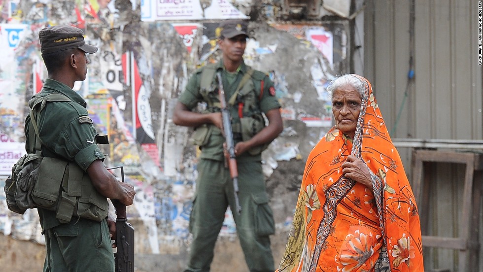 A Sri Lankan Muslim woman walks past soldiers following clashes between Muslims and Buddhists in the town of Aluthgama.