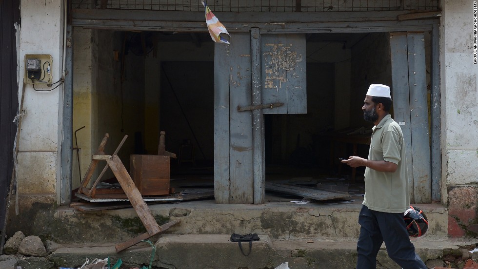 A Sri Lankan Muslim man walks past ransacked shops in Aluthgama.