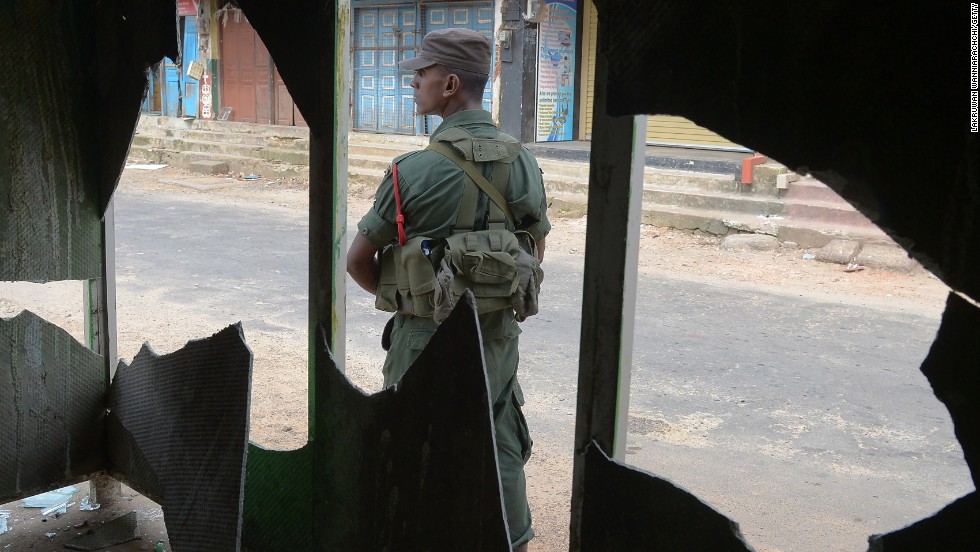 A soldier stands guard outside a smashed window.