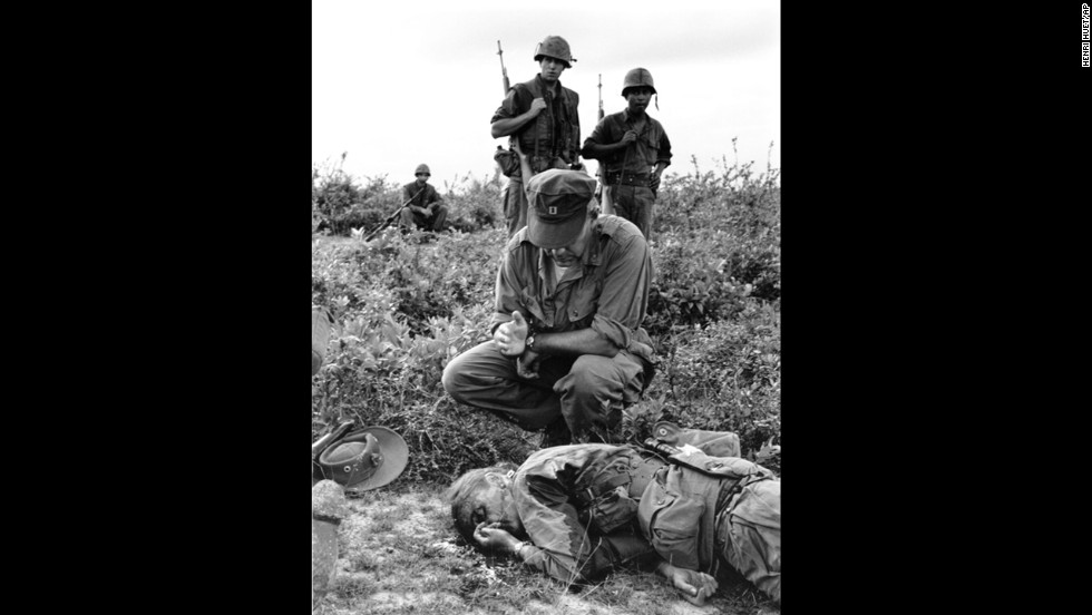 In this 1965 Henri Huet photograph, Chaplain John McNamara administers last rites to photographer Dickey Chapelle in South Vietnam. Chapelle was covering a U.S. Marine unit near Chu Lai for the National Observer when a mine seriously wounded her and four Marines. Chappelle died en route to a hospital, the first American woman correspondent ever killed in action.