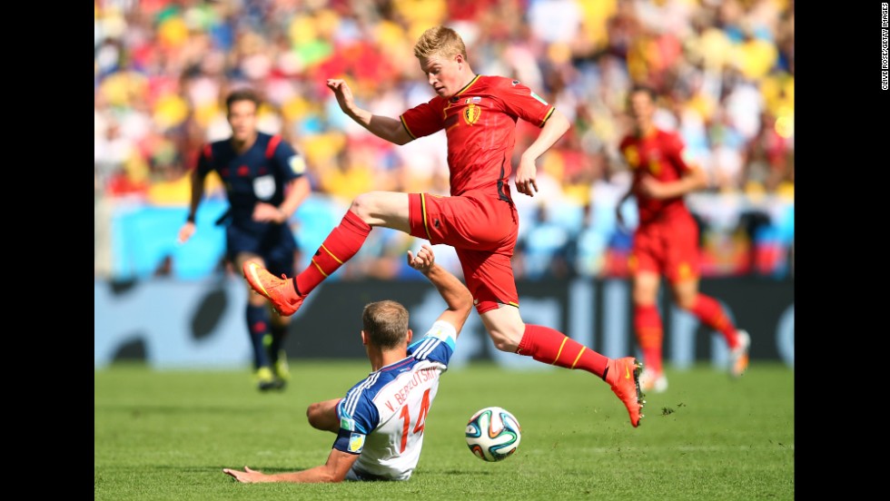 Kevin De Bruyne of Belgium tries to dodge a tackle by Vasily Berezutskiy of Russia.