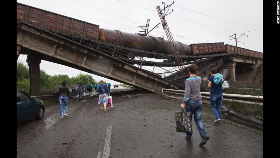 People walk under a destroyed railroad bridge near the village of Novobakhmutivka on Monday, July 7.