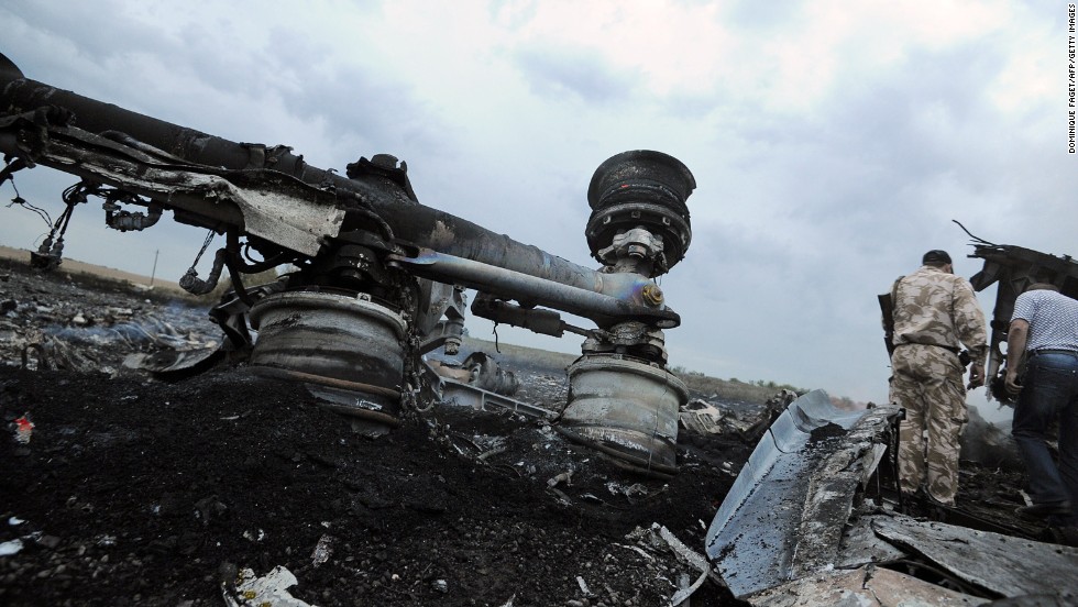 A man stands next to wreckage.