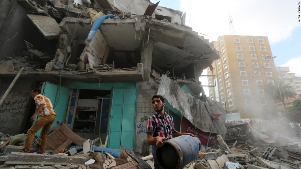 A Palestinian carries a gas cylinder salvaged from the rubble of an apartment building after it was hit by Israeli fire on July 18.