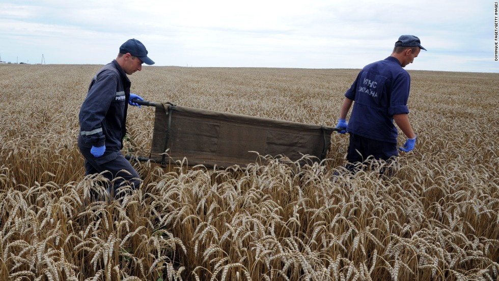 Ukrainian rescue workers walk through a wheat field with a stretcher as they collect the bodies of victims on July 19, 2014.