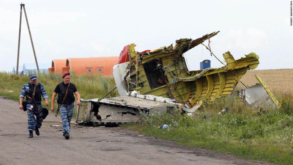 Armed rebels walk past large pieces of the Boeing 777 on July 19, 2014. 