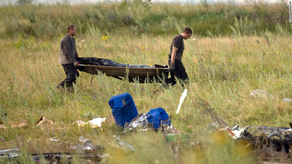 Emergency workers carry the body of a victim at the crash site on July 19, 2014. 