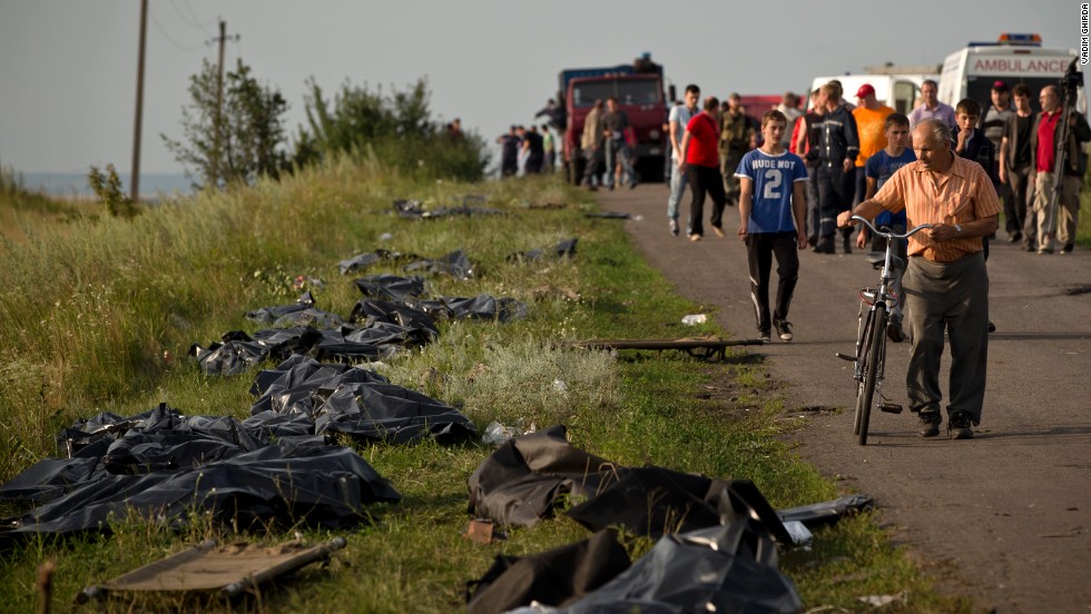 Victims&#39; bodies are placed by the side of the road on July 19, 2014, as recovery efforts continue at the crash site. International officials lament the lack of a secured perimeter.