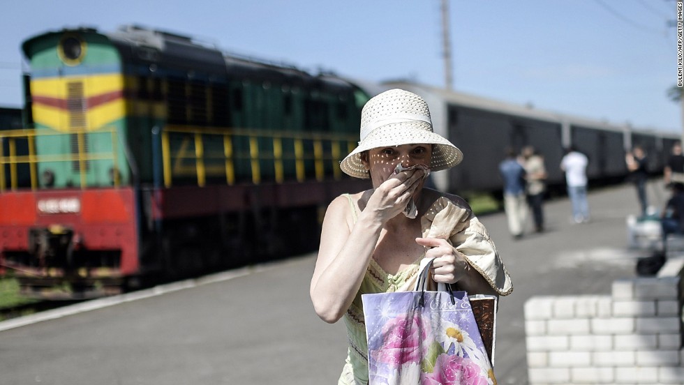 A woman covers her mouth with a piece of fabric July 20, 2014, to ward off smells from railway cars that reportedly contained passengers&#39; bodies.