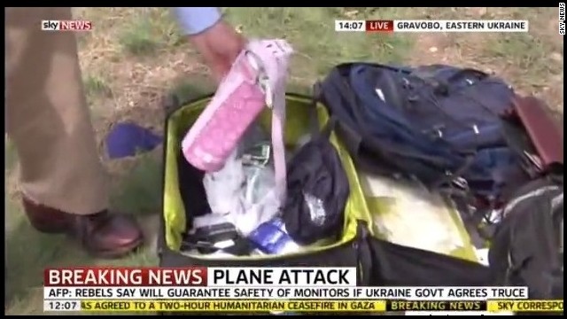 A reporter picks up the belongings of MH17 victims during a live Sky News broadcast at the crash site in eastern Ukraine.