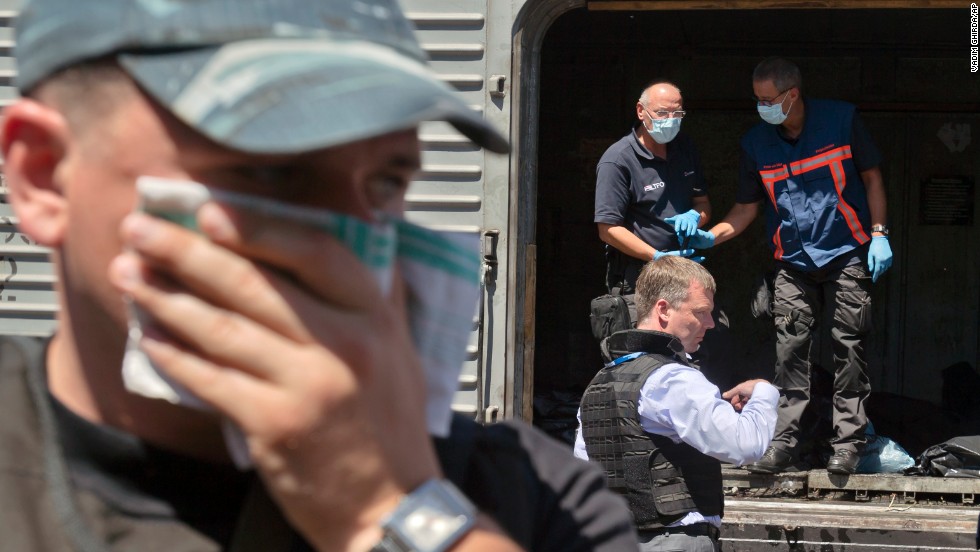 A man covers his face with a rag as authorities inspect bodies in a refrigerated train Monday, July 21. 
