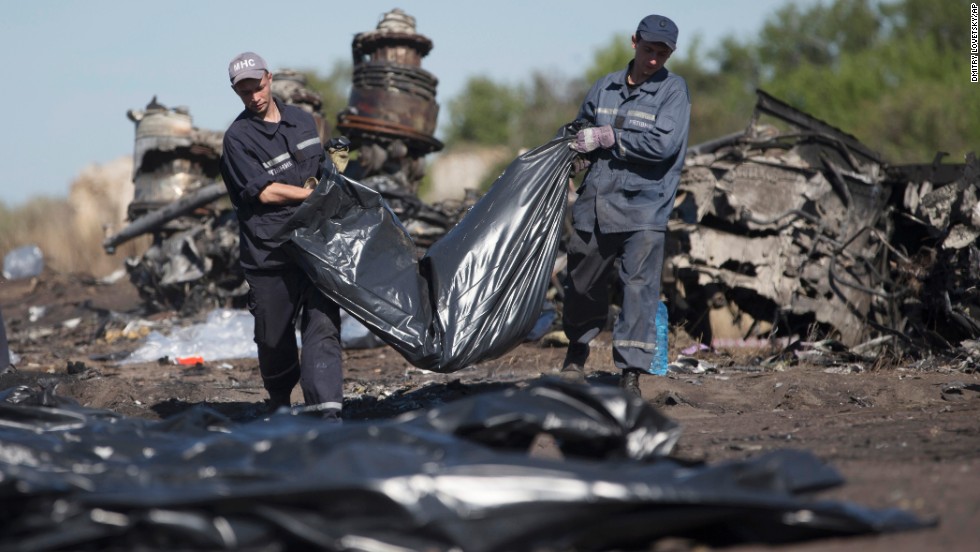 Emergency workers carry a victim&#39;s body in a bag at the crash site on July 21, 2014.