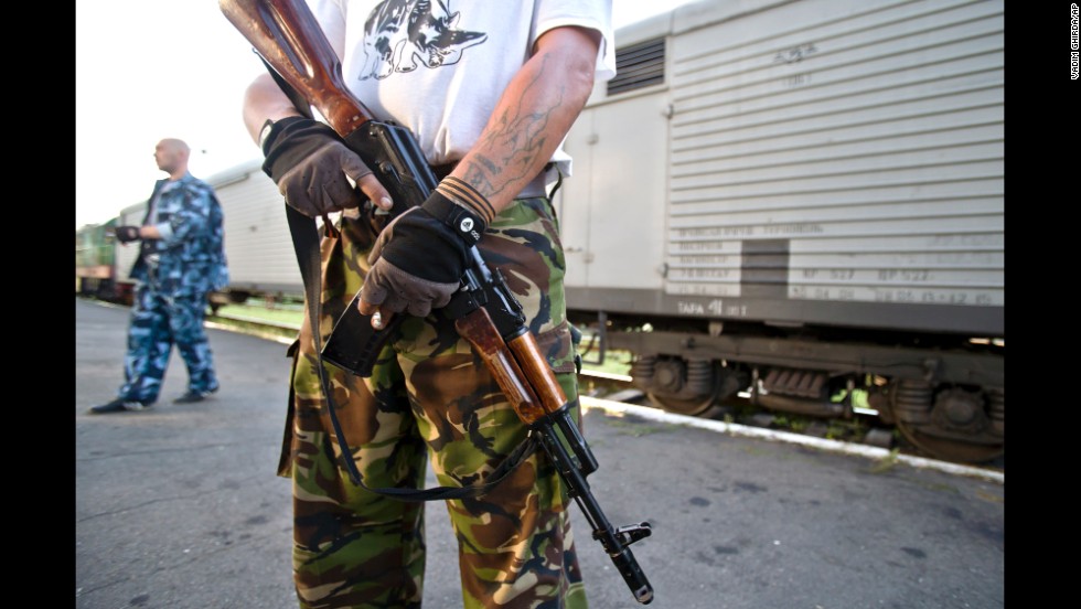 An armed pro-Russian rebel stands guard next to a refrigerated train loaded with bodies in Torez, Ukraine, on Sunday, July 20, 2014.