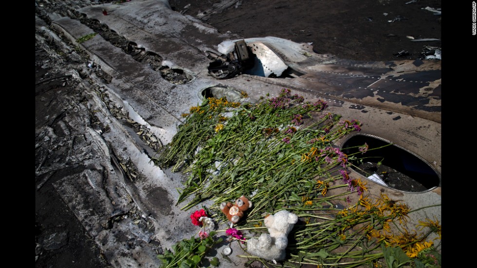 Toys and flowers sit on the charred fuselage of the jet as a memorial on July 20, 2014.