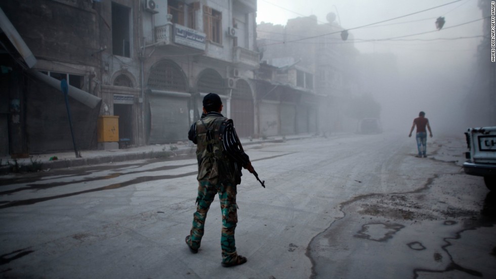 A rebel fighter stands on a dust-covered street in Aleppo on Monday, July 21.