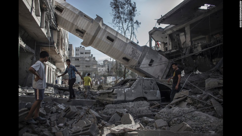 Palestinians walk under the collapsed minaret of a destroyed mosque in Gaza City on July 30.