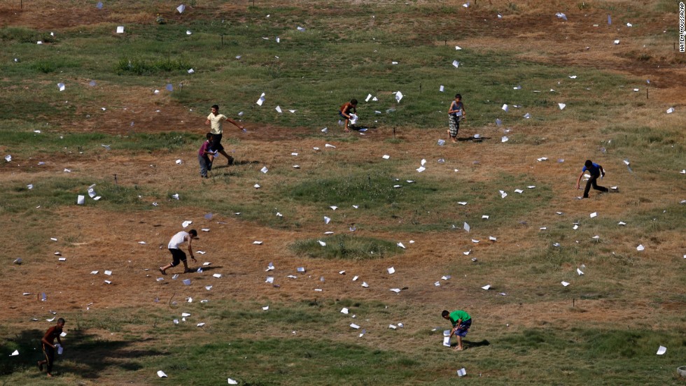 Palestinians gather leaflets that fell from an Israeli plane on July 30. The leaflets warned residents of airstrikes in Gaza City.