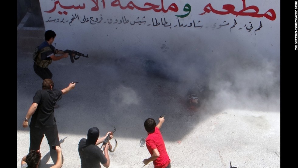 Rebel fighters execute two men Friday, July 25, in Binnish, Syria. The men reportedly were charged by an Islamic religious court with detonating several car bombs. 