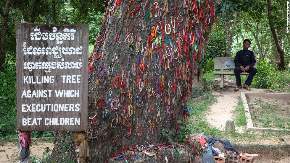 A Cambodian man sits in Choeung Ek Killing Fields near a tree that was used to beat children to death during the Khmer Rouge regime on August 6, 2014 in Phnom Penh, Cambodia.