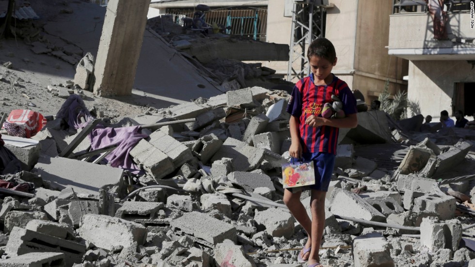 A Palestinian boy salvages family belongings from the rubble of a four-story building after an airstrike in Gaza City on Friday, August 8.