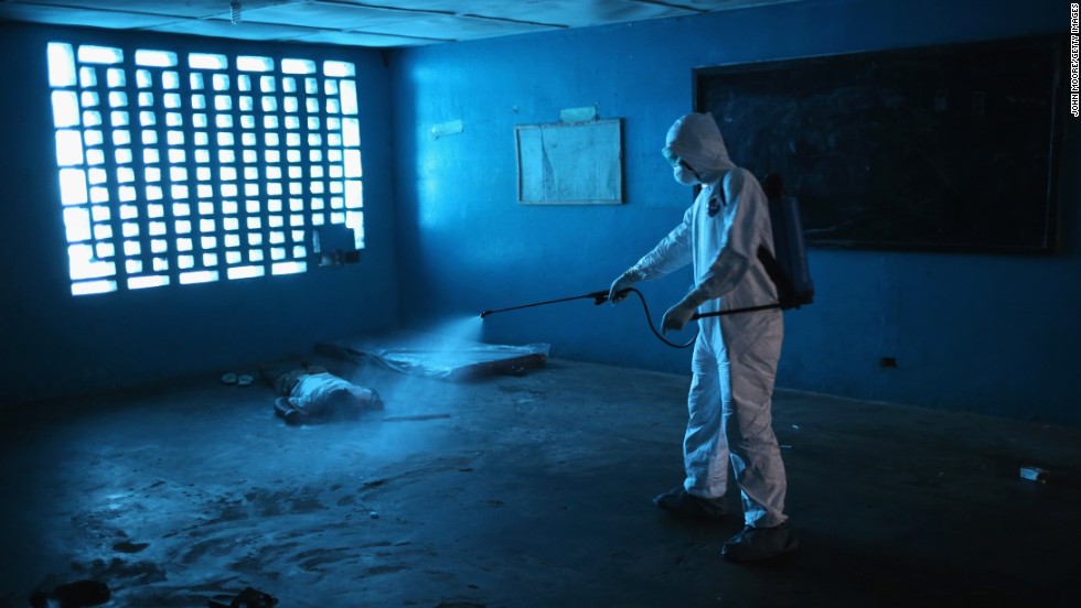 A health worker disinfects a corpse after a man died in a classroom being used as an Ebola isolation ward August 15, 2014, in Monrovia.