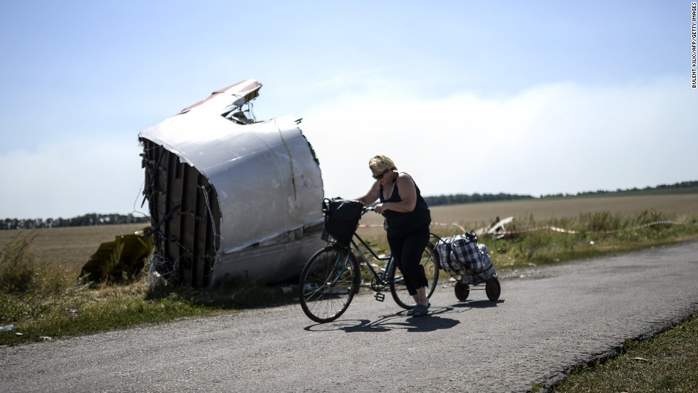 A woman walks with her bicycle near the crash site on August 2, 2014.