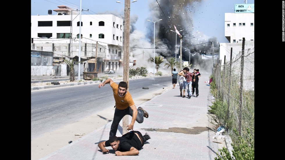 Palestinians run away from debris after a bomb from an Israeli airstrike hit a house in Gaza on Saturday, August 23.