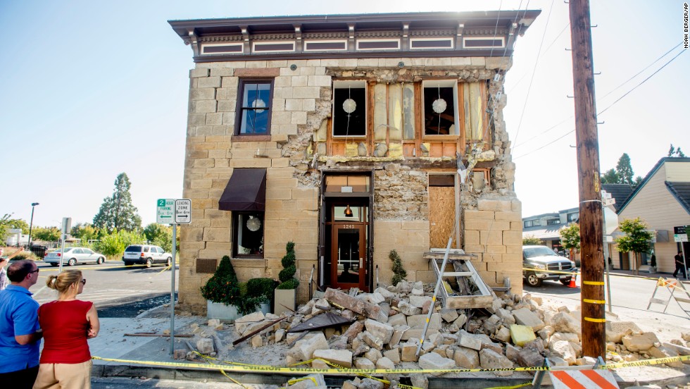 Pedestrians stop to examine a crumbling facade at the Vintner&#39;s Collective tasting room in Napa on August 24.