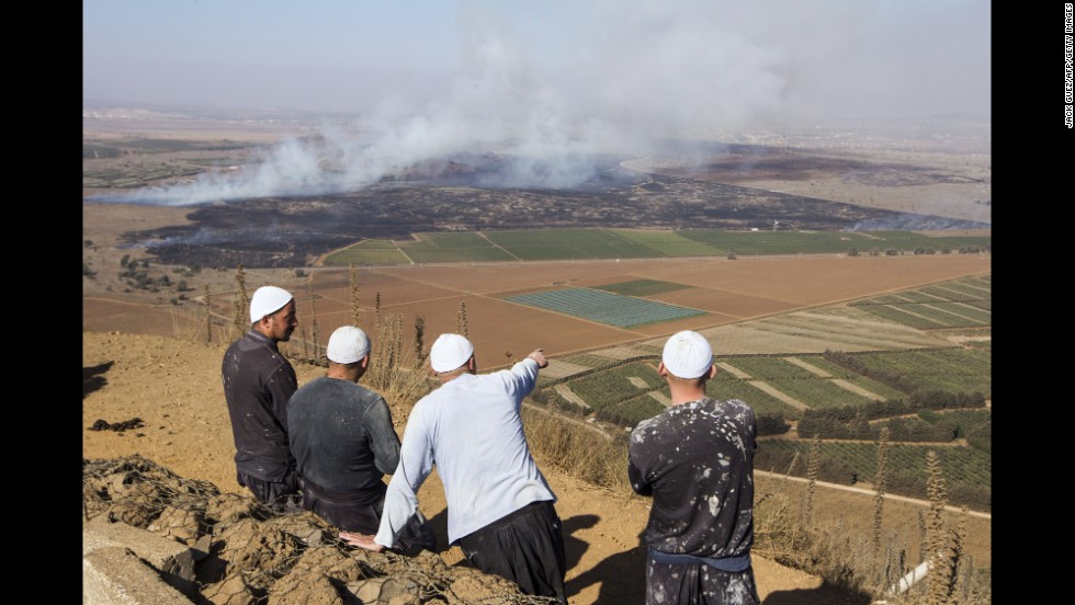 Druze men watch from the Golan Heights side of the Quneitra border with Syria as smoke rises during fighting between rebels and forces loyal to al-Assad on Wednesday, August 27. 