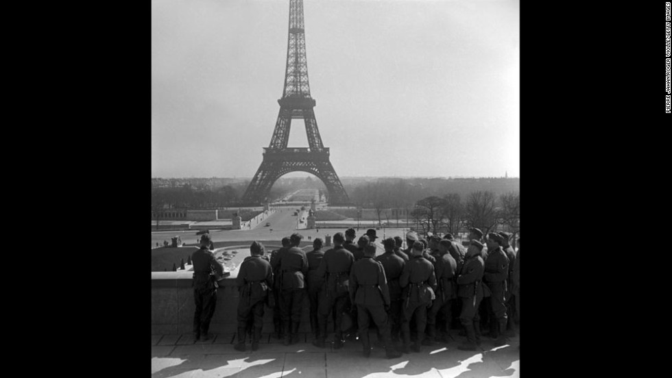 German soldiers on the Esplanade du Trocadero view the Eiffel Tower. In June 1940, German troops marched into Paris, forcing France to capitulate and establish the pro-Axis Vichy French government.