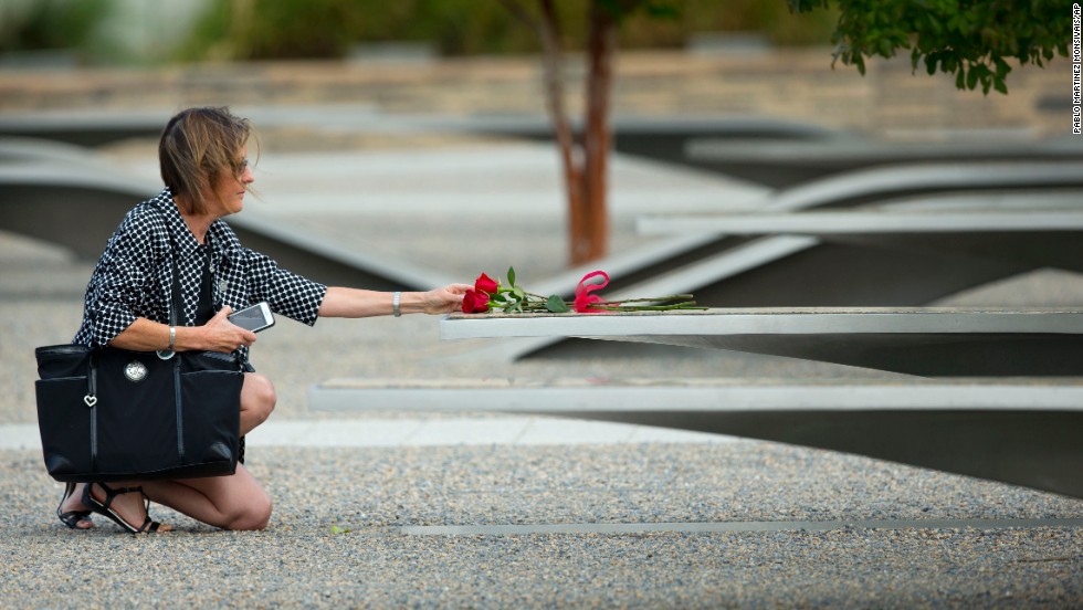 A woman reaches out to touch a rose on one of the benches at the Pentagon Memorial. 